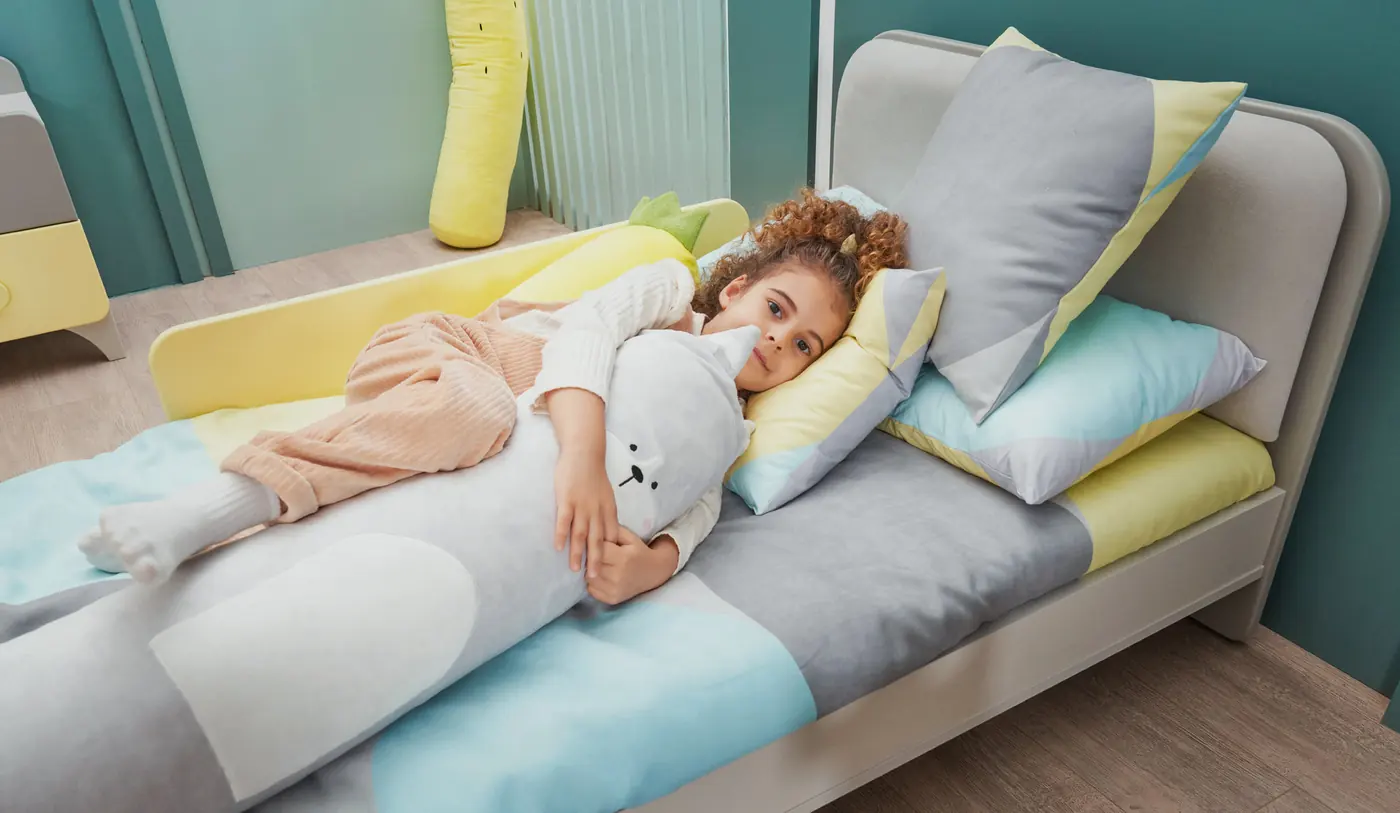Child resting on a bed with an upholstered headboard